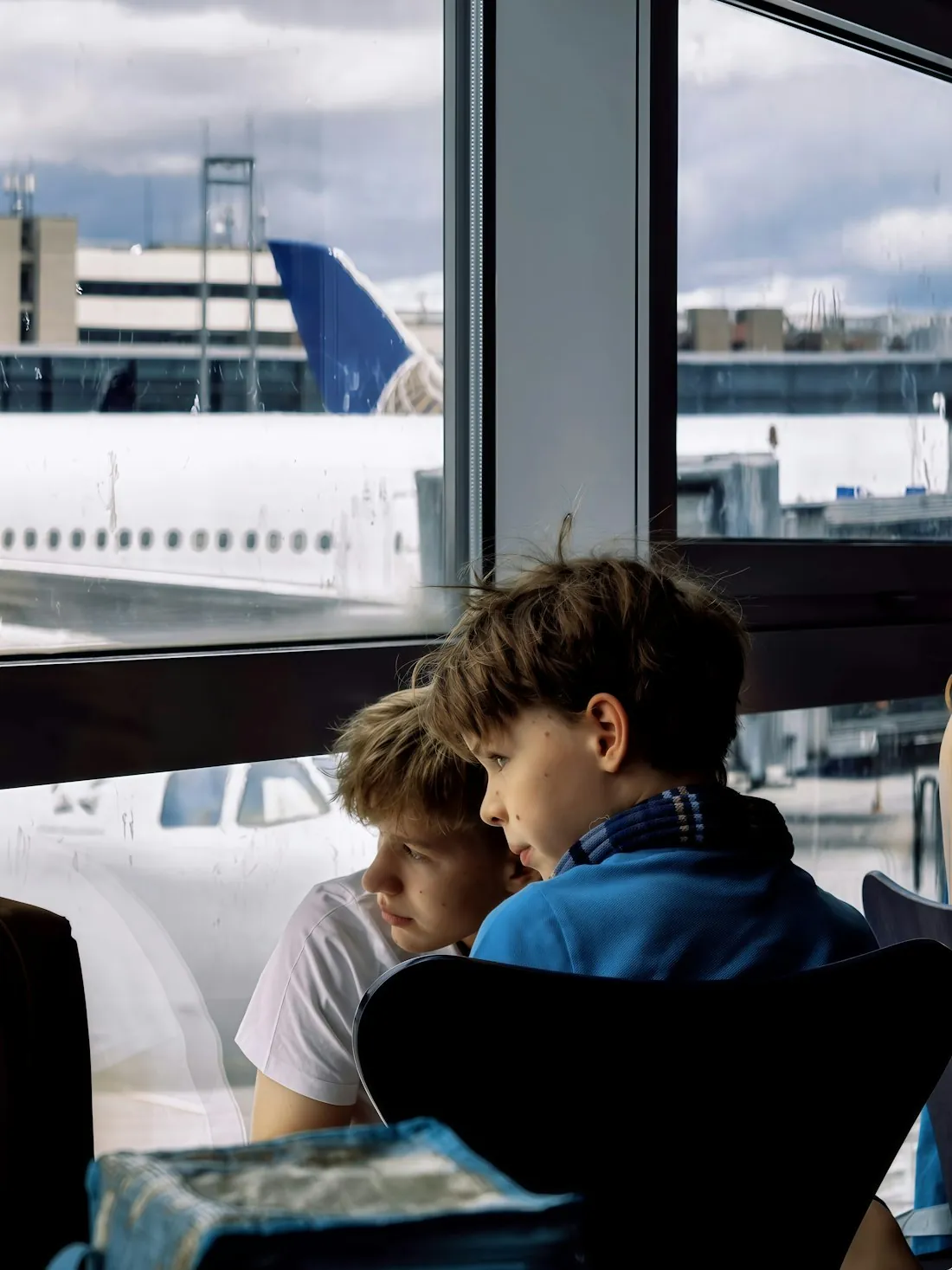 Two children watching planes together at the terminal window