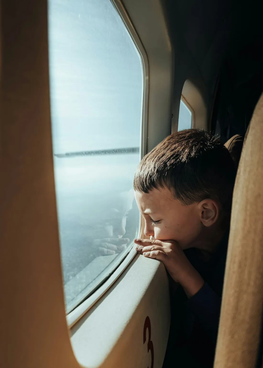 A young child gazing out of an aircraft window at the view