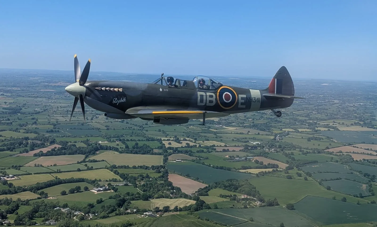 A Spitfire flying past over green English countryside