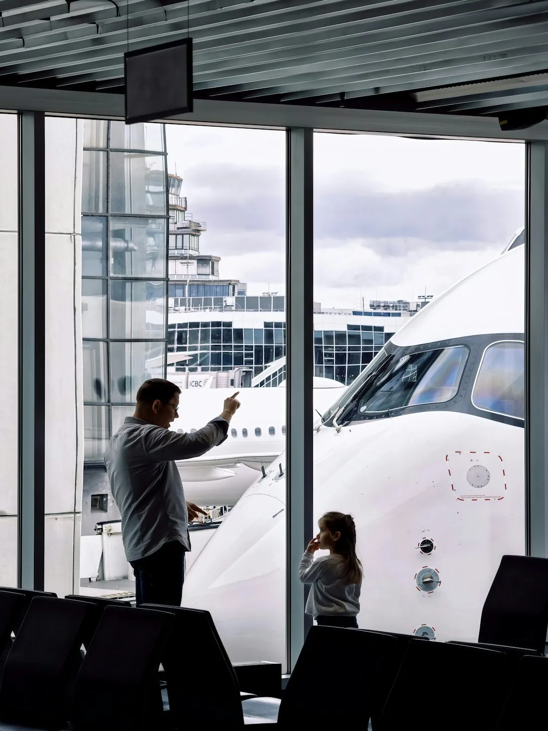 A family watching a jet together through the airport terminal window